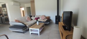 A modern living room with a sofa, ottoman, coffee table, and a television on a wooden stand. - Villa unique ,piscine et foret (Gonfaron)