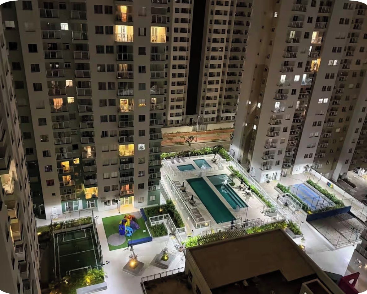 A high-rise residential building with multiple balconies, a rooftop pool area, and a children's play area.