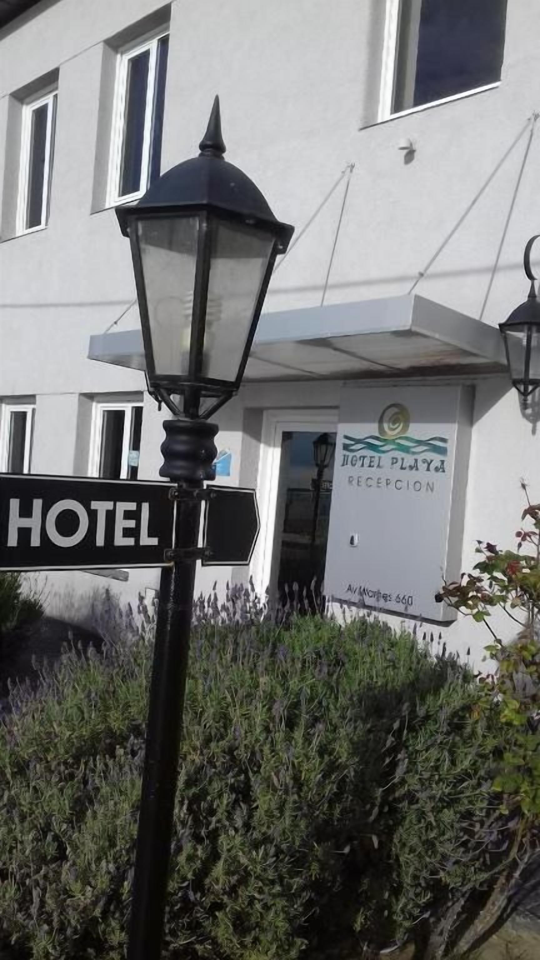 Señal de hotel con un cartel de recepción, una farola y la fachada de un edificio.