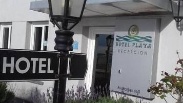 Señal de hotel con un cartel de recepción, una farola y la fachada de un edificio.