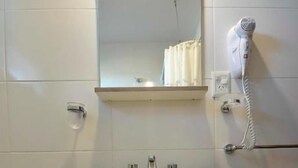 A bathroom with a white sink, a mirror above it, a towel rack, and a hairdryer on the wall. - Hotel Playa (Comodoro Rivadavia)