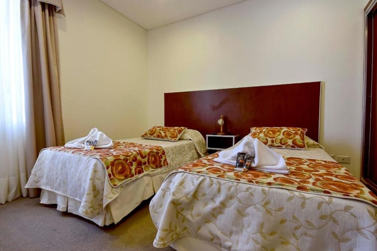 Een hotelkamer met twee bedden, elk met een bloemenbedekker en een handdoek.