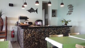 A kitchen area with a stone island, hanging pendant lights, and a fish wall decoration. - Hotel Playa (Comodoro Rivadavia)
