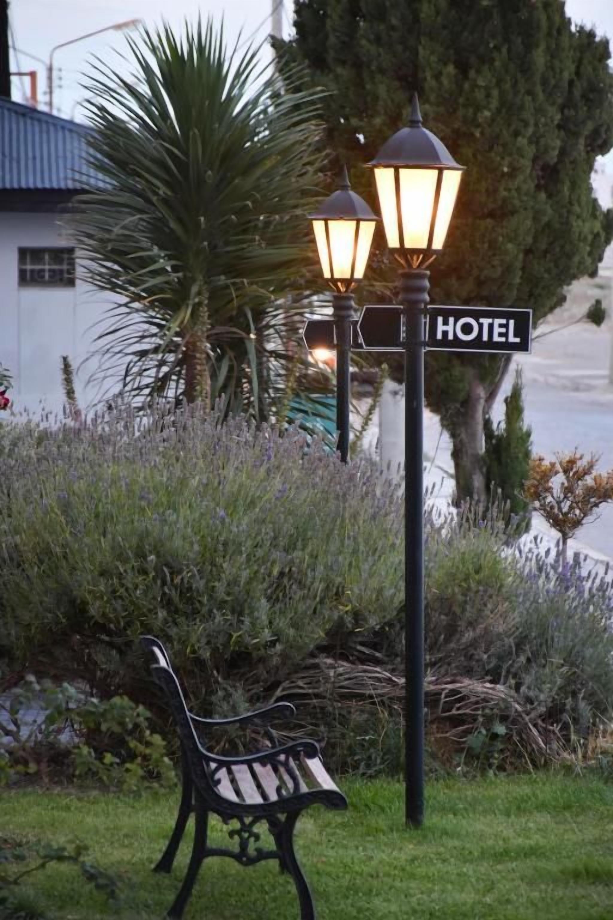 Un banco, una señal de calle y un poste de luz con un letrero que dice 'HOTEL'.