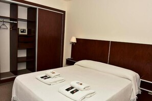 Habitació d'hotel amb un llit, un armari i una taula de nit.