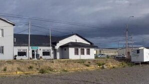 A two-story building with a flat roof, a small attached structure, and a paved area in front. - Hotel Playa (Comodoro Rivadavia)