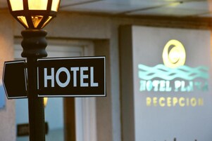 Un letrero de hotel con la palabra 'HOTEL' y una zona de recepción al fondo.