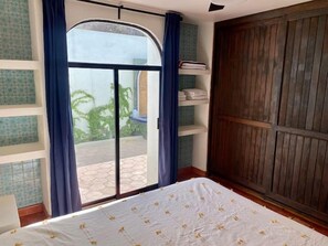 A bedroom with a bed, a sliding glass door to a patio, and a wooden wardrobe. - 4 Bedroom home-amazing location in downtown Cabo San Lucas (Cabo San Lucas)