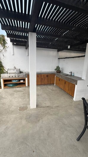 An outdoor kitchen area with a grill, wooden cabinets, and a concrete floor. - 4 Bedroom home-amazing location in downtown Cabo San Lucas (Cabo San Lucas)