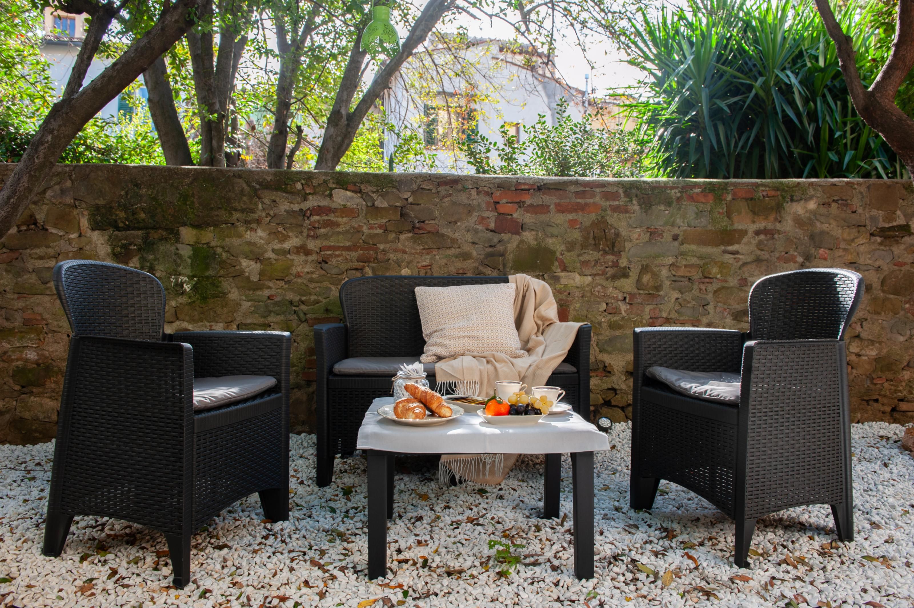 Een terras met rieten meubels, een tafel met eten en een stenen muur.