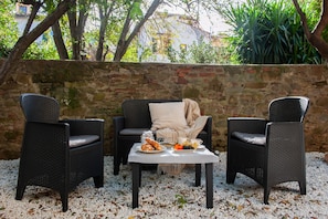 A patio area with wicker furniture, a table with food, and a stone wall. - Outside ZTL • Easy parking • 15 min from the Duomo (FIRENZE)
