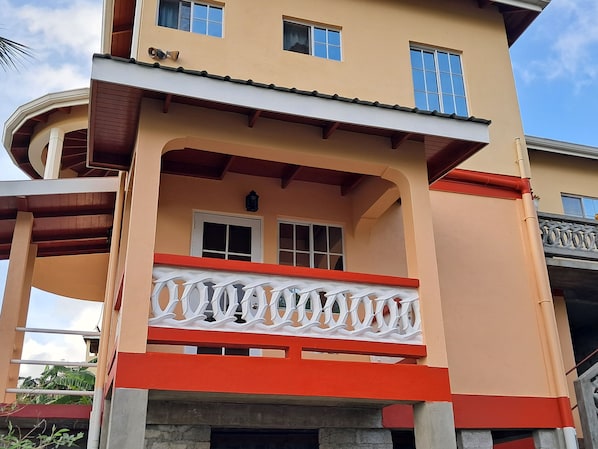 A multi-story building with a balcony, a window, and a door.
