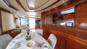 Un'area pranzo con un tavolo apparecchiato per quattro persone, un vaso con fiori e vista sul mare attraverso le finestre.