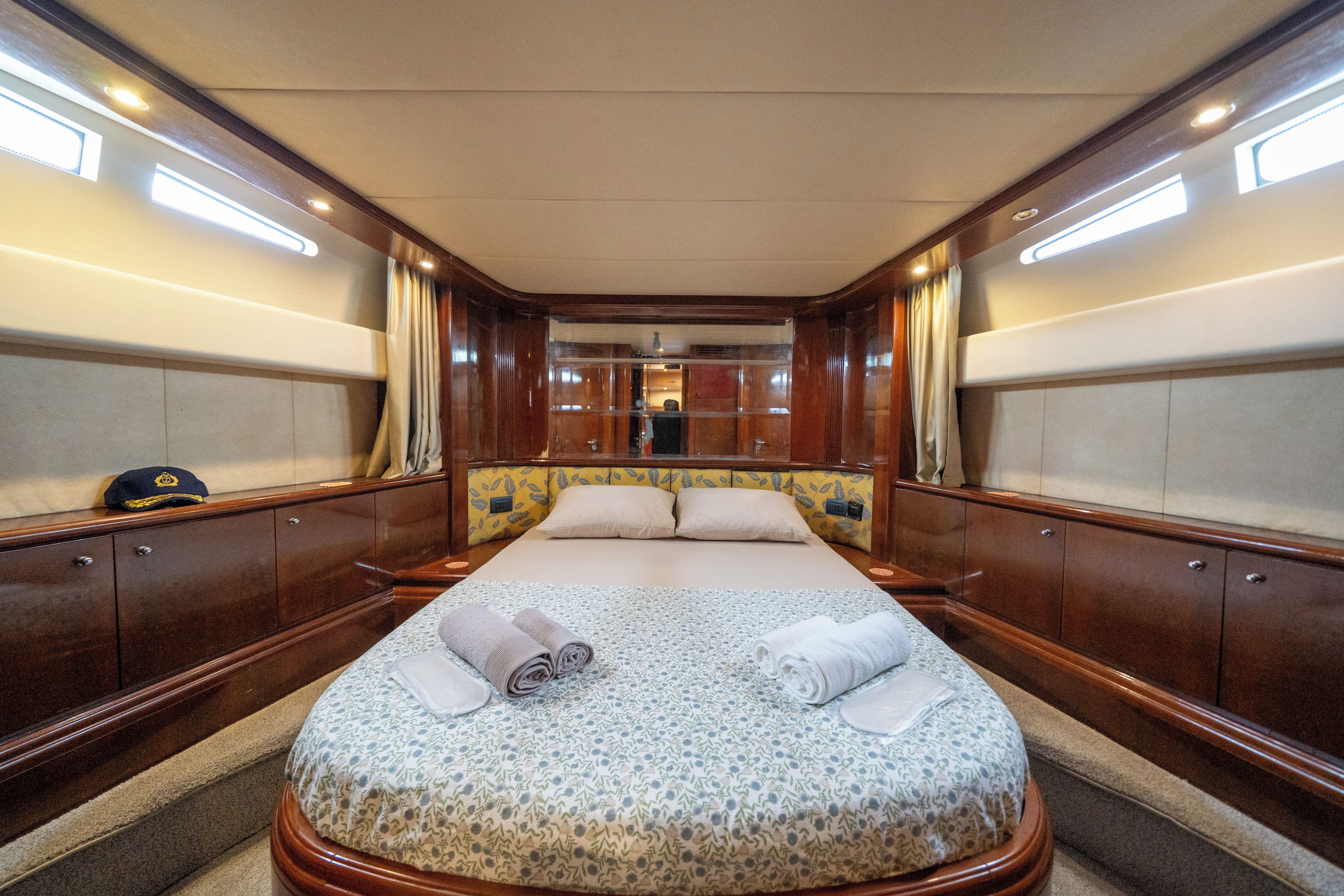 Una cabina spaziosa con un ampio letto, pannelli in legno e vista sull'interno della nave.