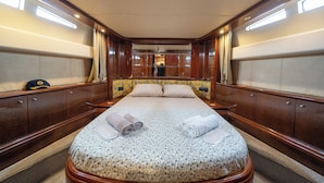 Una cabina spaziosa con un ampio letto, pannelli in legno e vista sull'interno della nave.