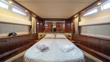Una cabina spaziosa con un ampio letto, pannelli in legno e vista sull'interno della nave.