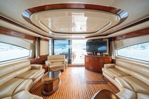 A yacht interior with leather seating, a wooden floor, and a TV.