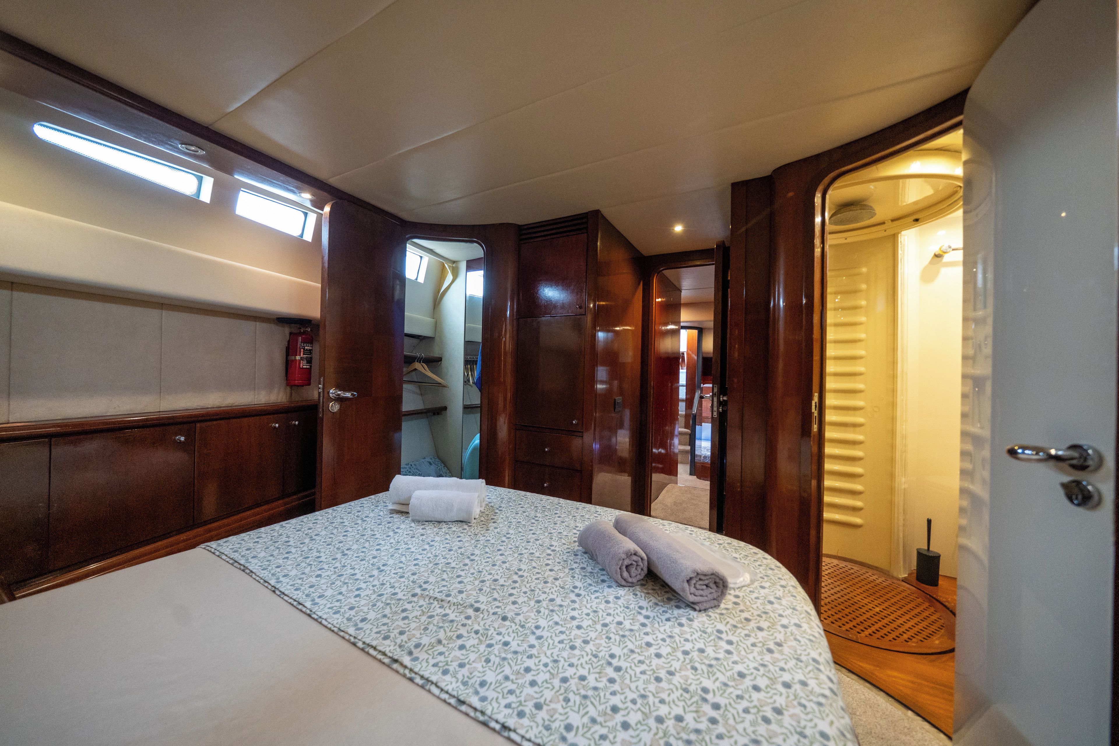 Quarto compacto e bem iluminado, com cama, guarda-roupa e porta para um banheiro.