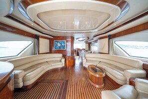 A luxurious interior with curved seating, a central table, and a view of the outside. - Barans Boat (Göcek)