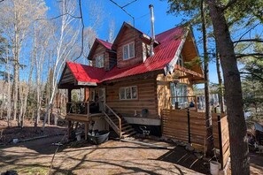 Une cabane en rondins avec un toit rouge, une véranda et un petit bateau au premier plan.