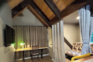 A cozy room with a wooden desk, a chair, and a patterned sofa. - Algonquin HappyForest Cottage-Canadian Highlander's Eco-Log Home at Kushog Lake (Algonquin Highlands)