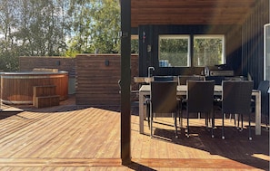 An outdoor deck with a hot tub, a grill, and a dining area with chairs and tables. - Amazing home in Struer with sauna (Struer)