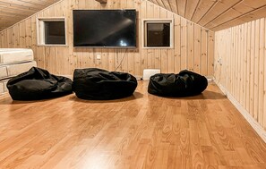 A room with wooden walls, a flat-screen TV mounted above a sofa, and a small window. - Amazing home in Struer with sauna (Struer)
