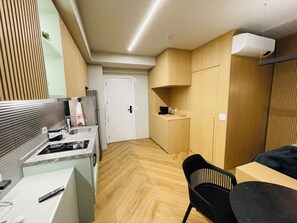 A compact kitchen with a sink, stove, and a small refrigerator. There is a dining area with a table and chairs. - Studio Nex One Itaim (São Paulo)