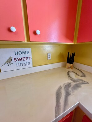 Una cucina con mobili rosa, un piano di lavoro e un cartello con la scritta 'HOME SWEET HOME'.