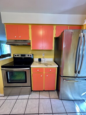 Una cucina con frigorifero in acciaio inossidabile, piano cottura e mobili dipinti in un colore vivace.
