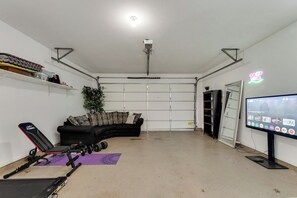 A home gym with exercise equipment, a couch, and a TV. - Light-filled 6-bedroom furnished home, 3,300 sqft, monthly stays (Plano)