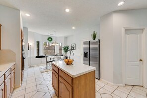 A kitchen with a central island, stainless steel appliances, and a dining area with a chandelier. - Light-filled 6-bedroom furnished home, 3,300 sqft, monthly stays (Plano)