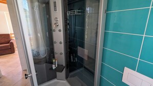 A glass-enclosed shower stall with a control panel, a white toilet, and teal tiled walls. - Apartment just a few meters from the beach (Quartu Sant'Elena)