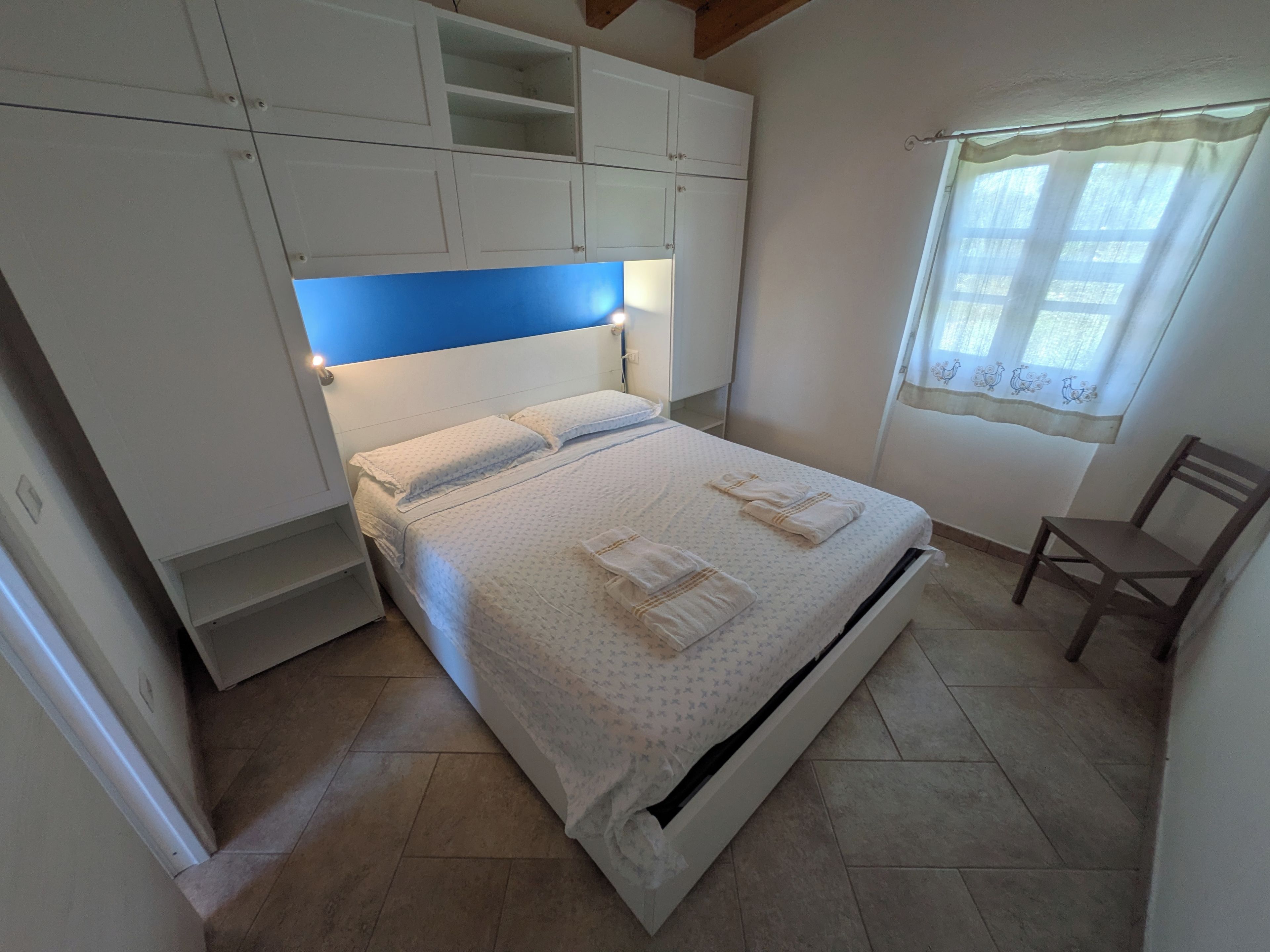 A bedroom with a bed, a chair, and built-in cabinets.