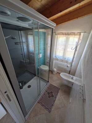 Een badkamer met een douchecabine, toilet, wastafel en bad.