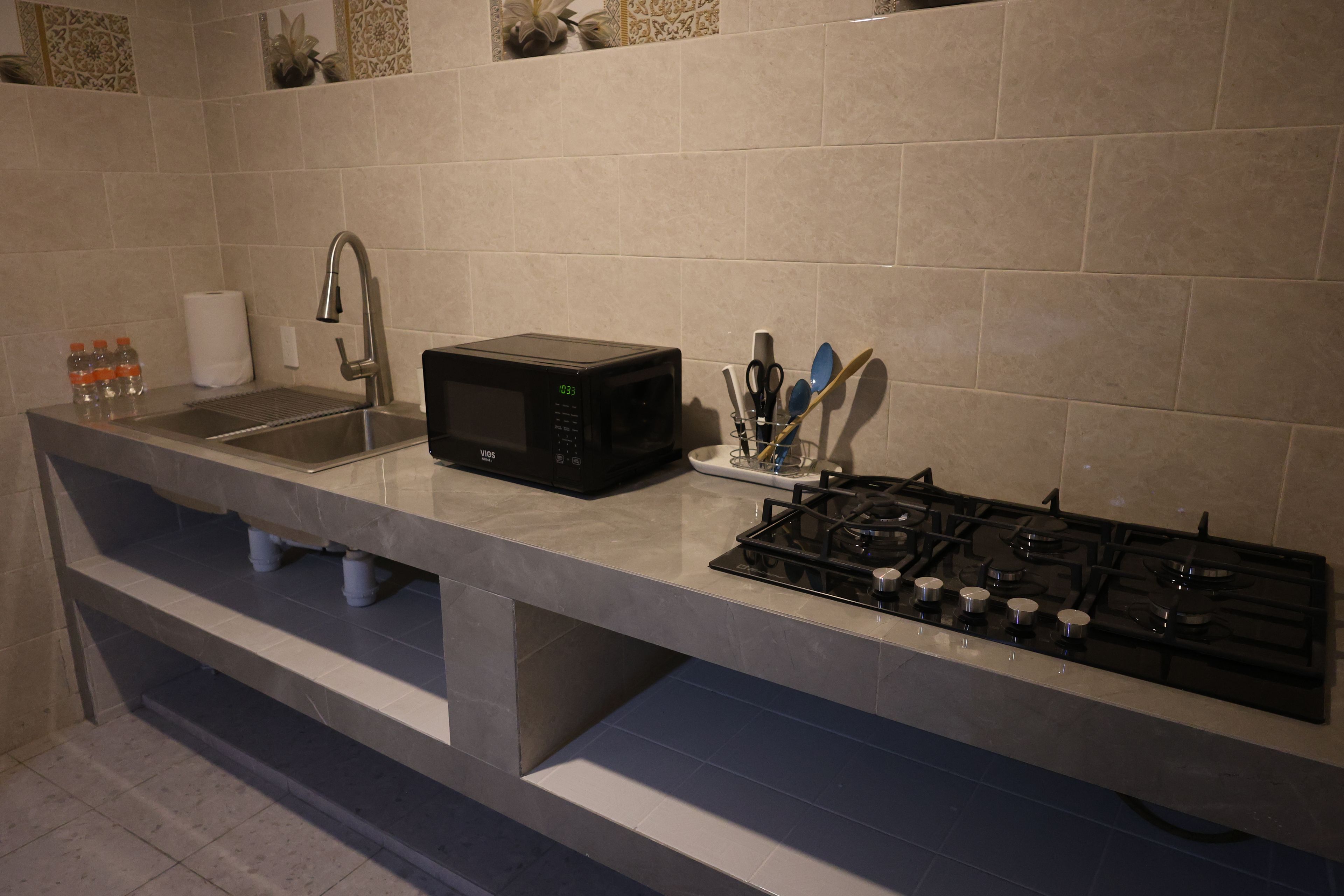 A kitchen with a stainless steel sink, a black microwave, and a gas stove.