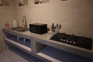 A kitchen with a stainless steel sink, a black microwave, and a gas stove.