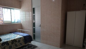 Une chambre à coucher comprenant un lit, une armoire et une porte coulissante donnant accès à un placard.