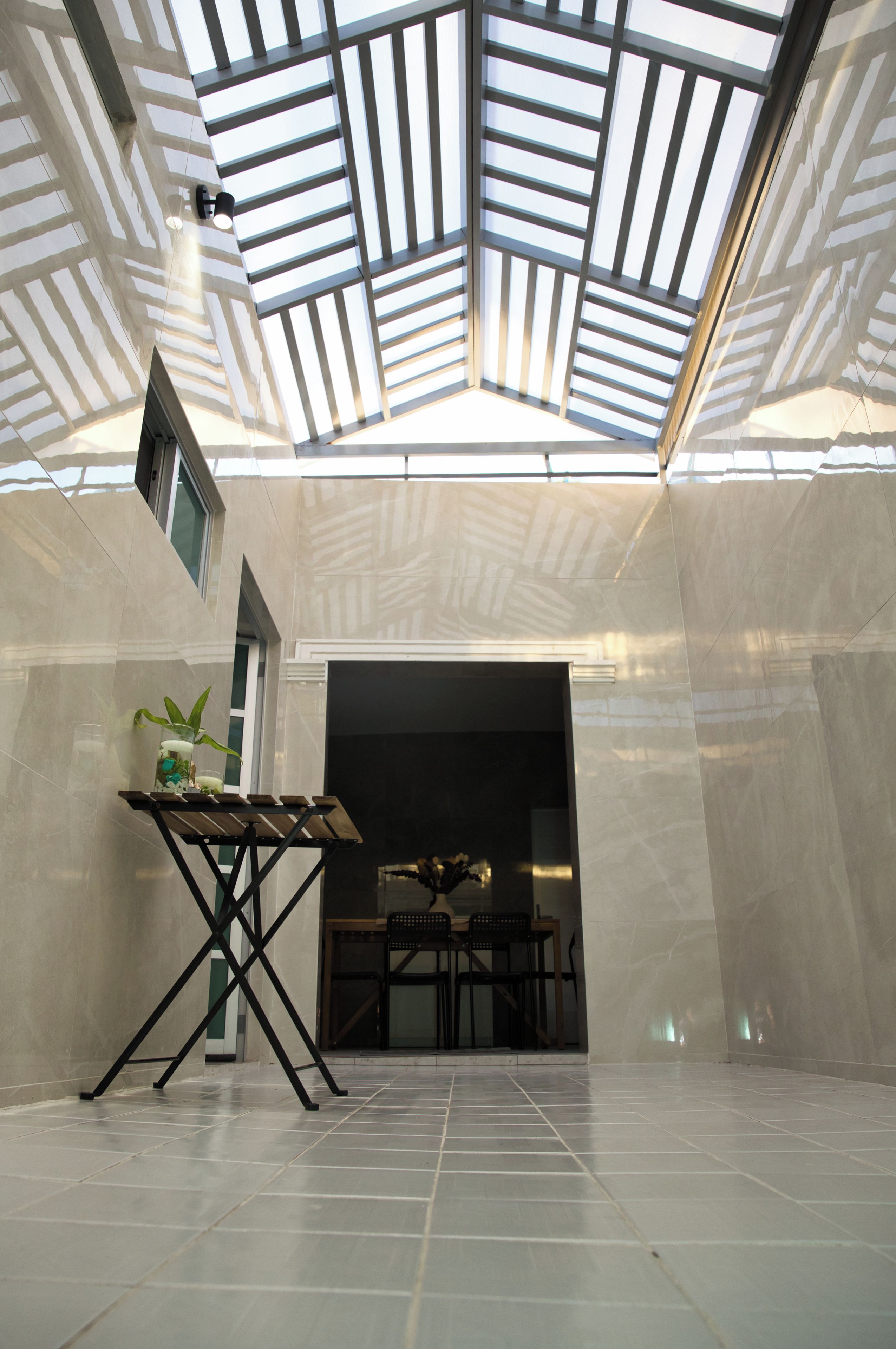 A modern interior with a skylight ceiling, a dining area with chairs and a table, and a potted plant.