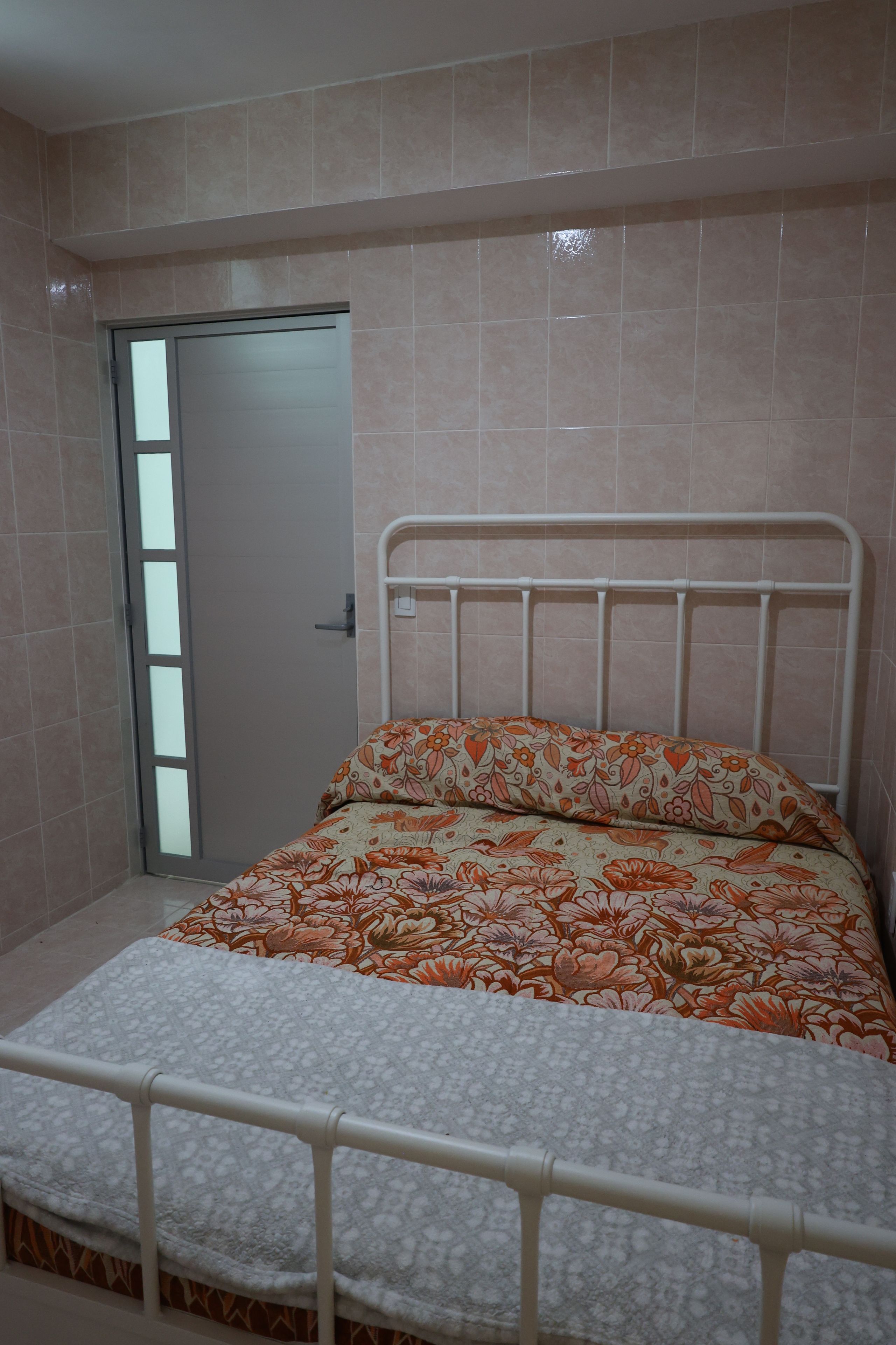 Quarto com cama, porta e corrimão branco.