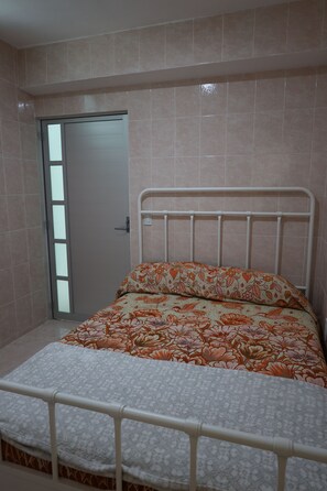 A bedroom with a bed, a door, and a white railing.