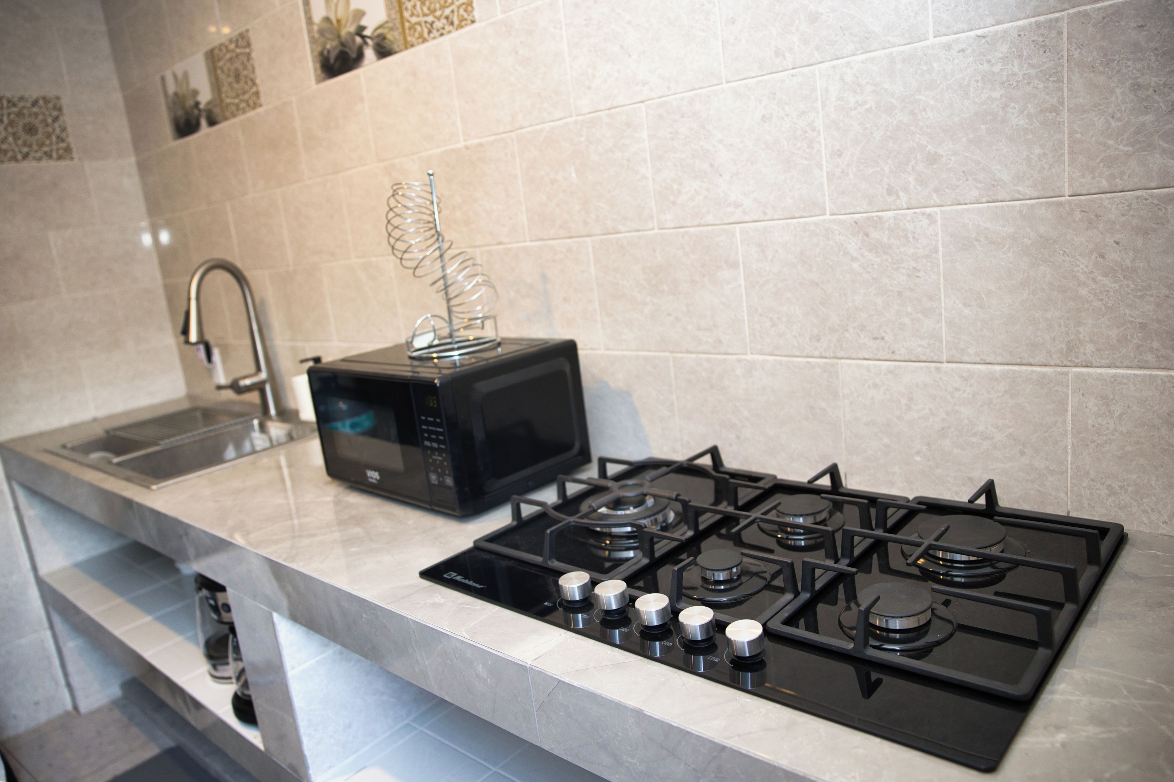 A kitchen with a gas stove, a microwave, and a sink.