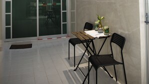 Un patio abrité avec une table et des chaises, une petite fenêtre et une porte.