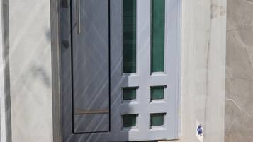 A white door with a number '2133' above it, a doormat with 'WELCOME' and a keyhole, and a small window with a green-tinted glass.