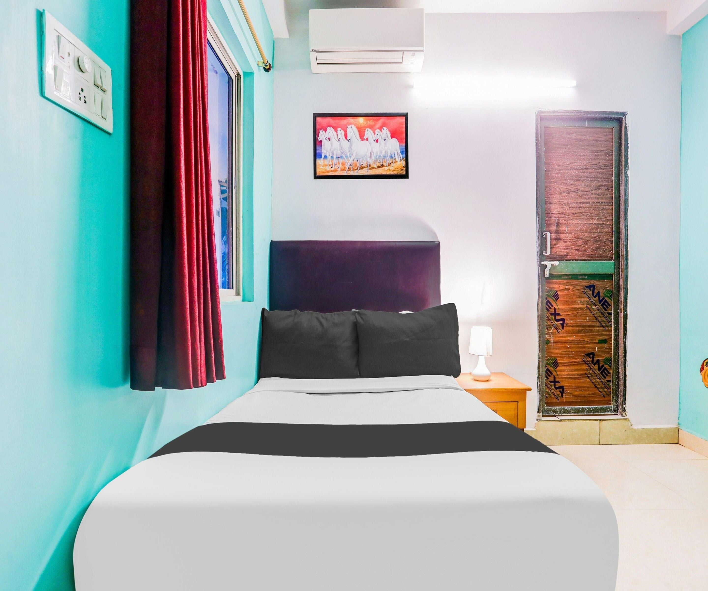 A hotel room with a bed, a nightstand, a lamp, a painting, and a door.