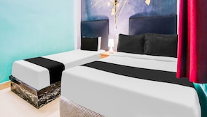 Een hotelkamer met twee bedden, een nachtkastje, een lamp en een decoratief wandobject.