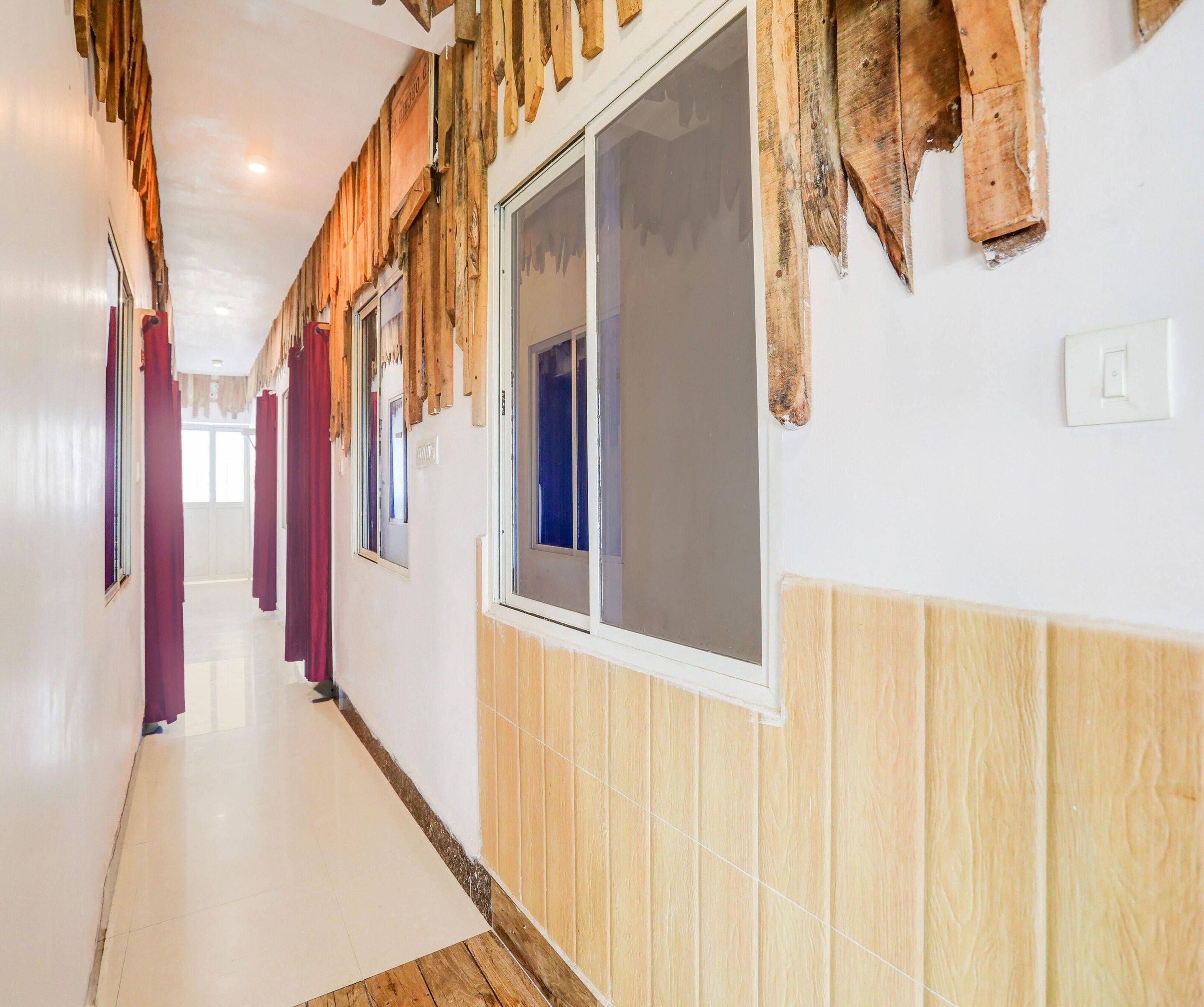 A hallway with wooden paneling, a tiled floor, and a window with a view.