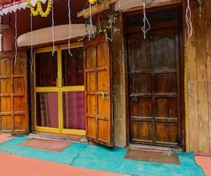 A wooden door with a yellow frame, a red curtain, and a small porch area with a blue mat.