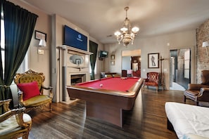 Ein Zimmer mit Poolbillardtisch, Kamin und Billiardausstattung.