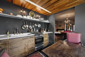 Une cuisine moderne avec des meubles en bois, une cuisinière et des casseroles suspendues.